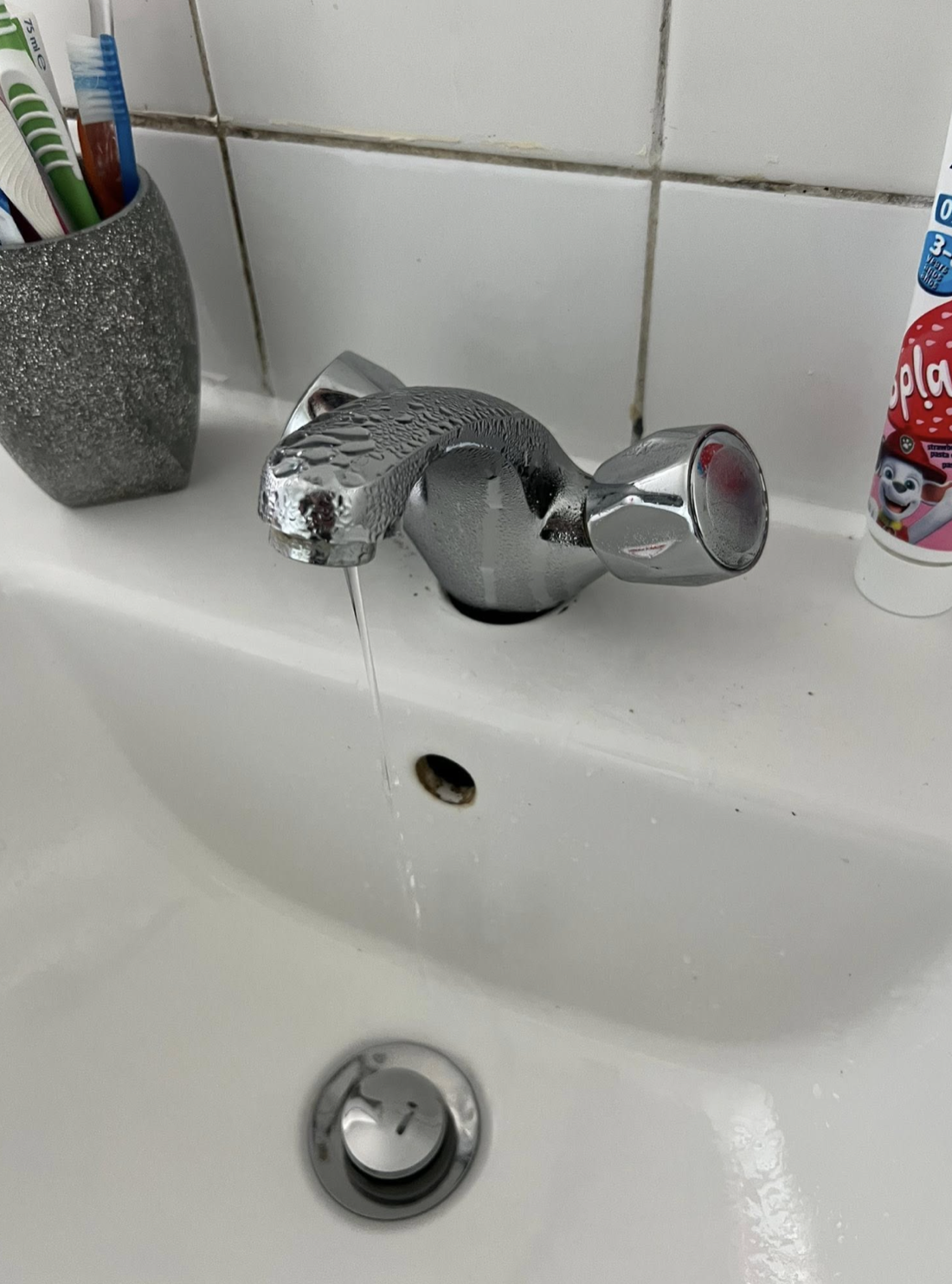 Old worn basin tap, dripping and covered in condensation